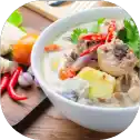 Bowl of spicy Thai soup with ingredients.