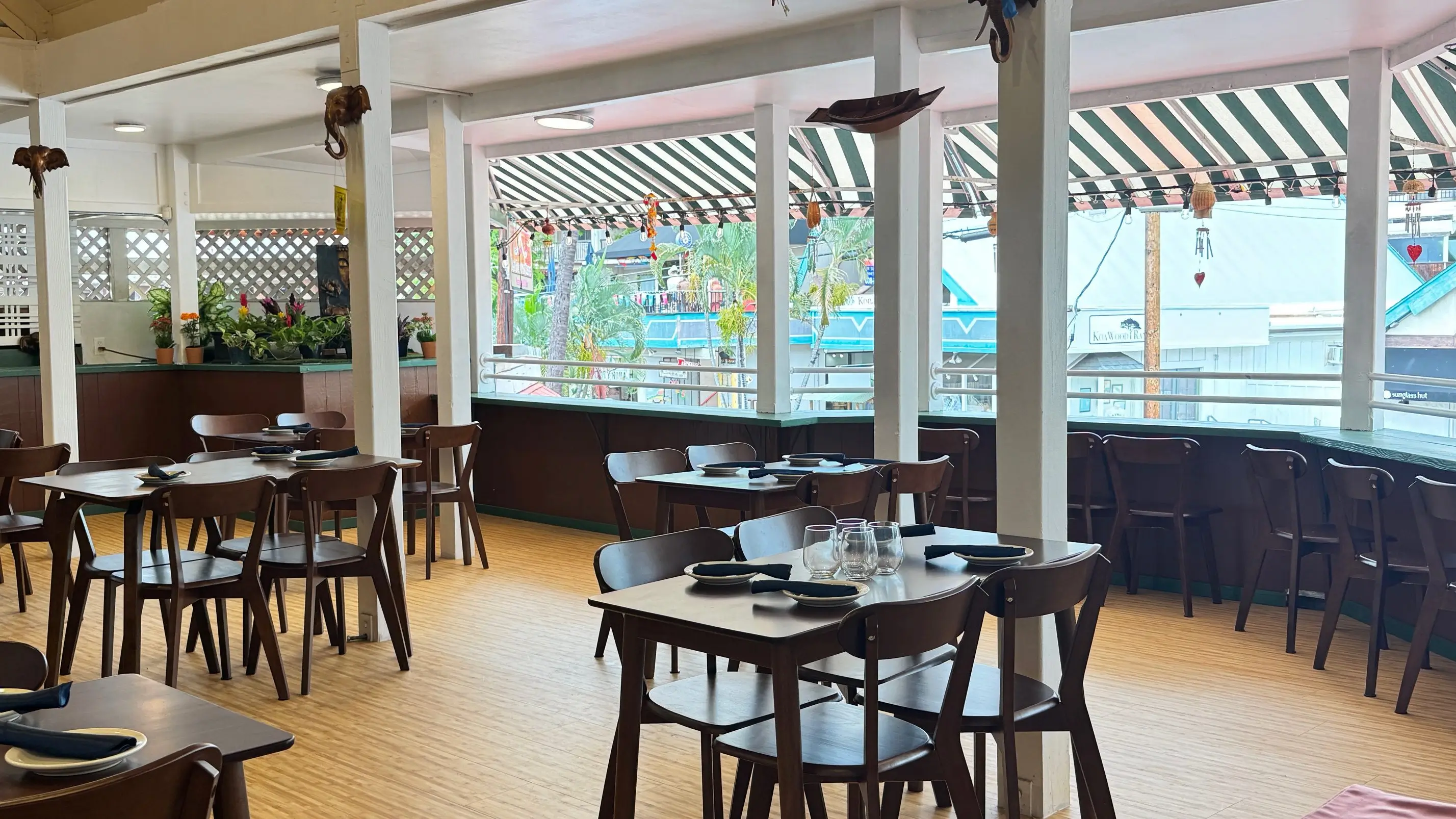 Open-air restaurant with wooden tables and chairs.